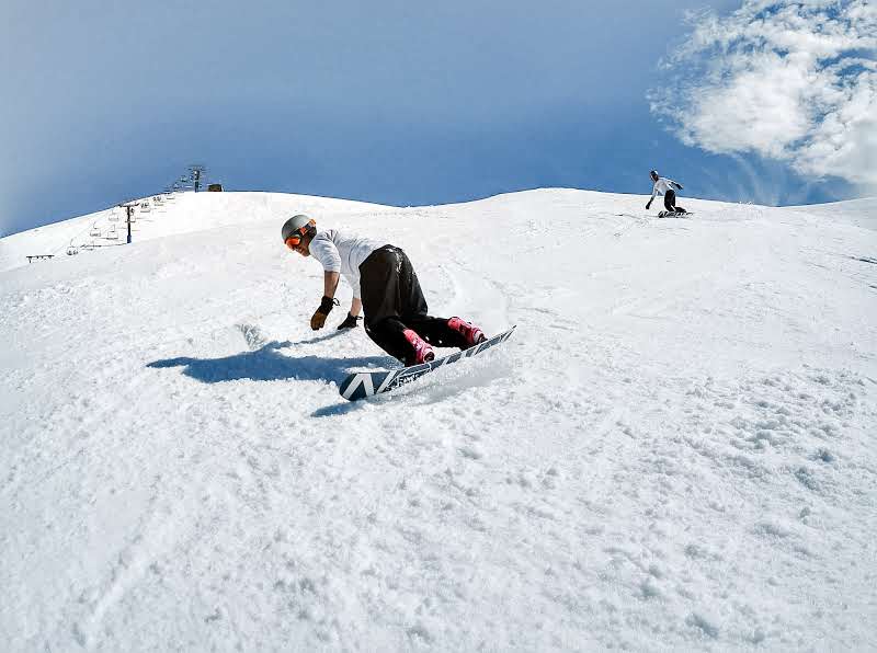 A man snowboarding down a ski run at mount hotham ski resort