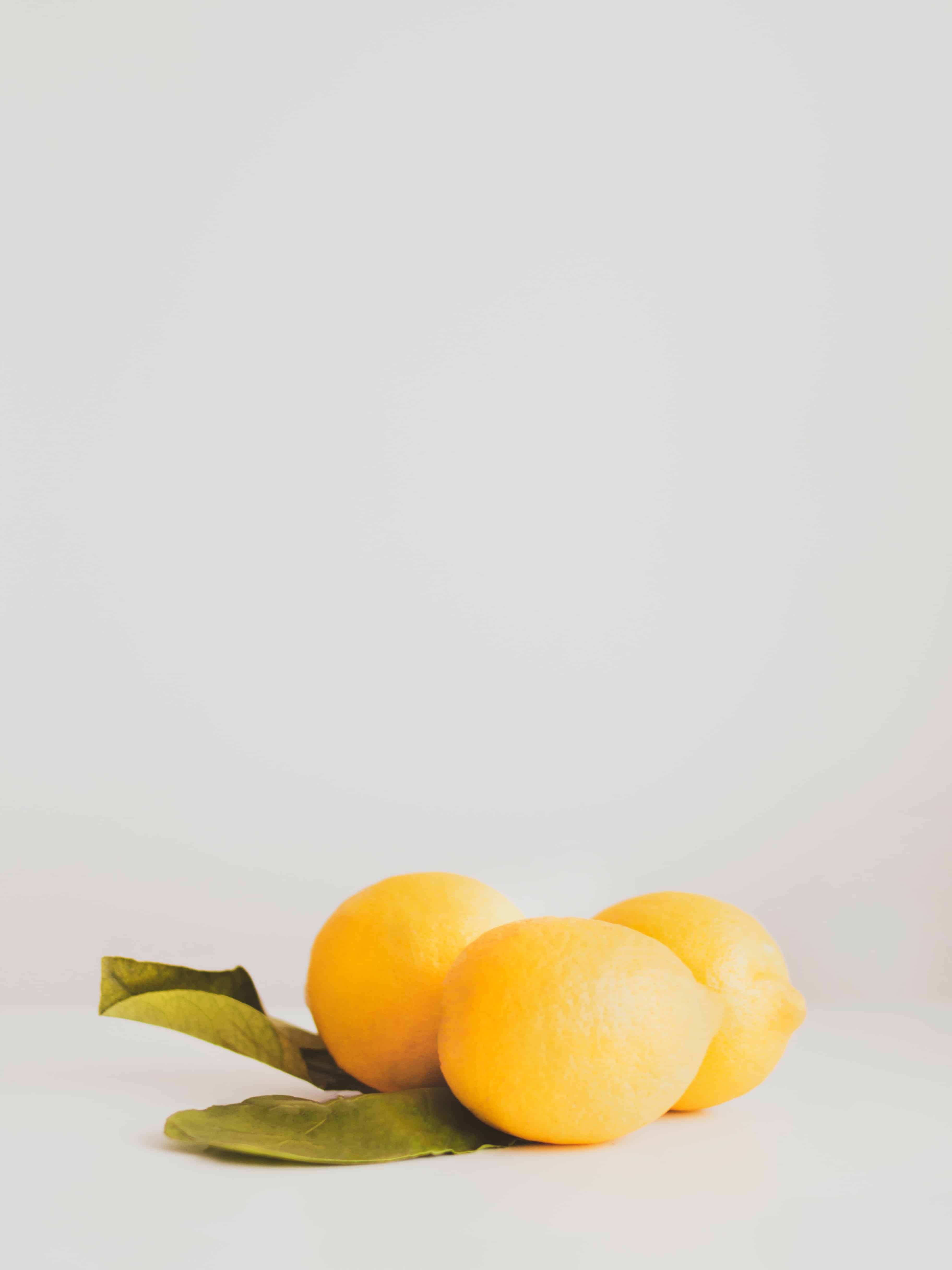 bright yellow lemons sitting on a white surface before being made into lemonade