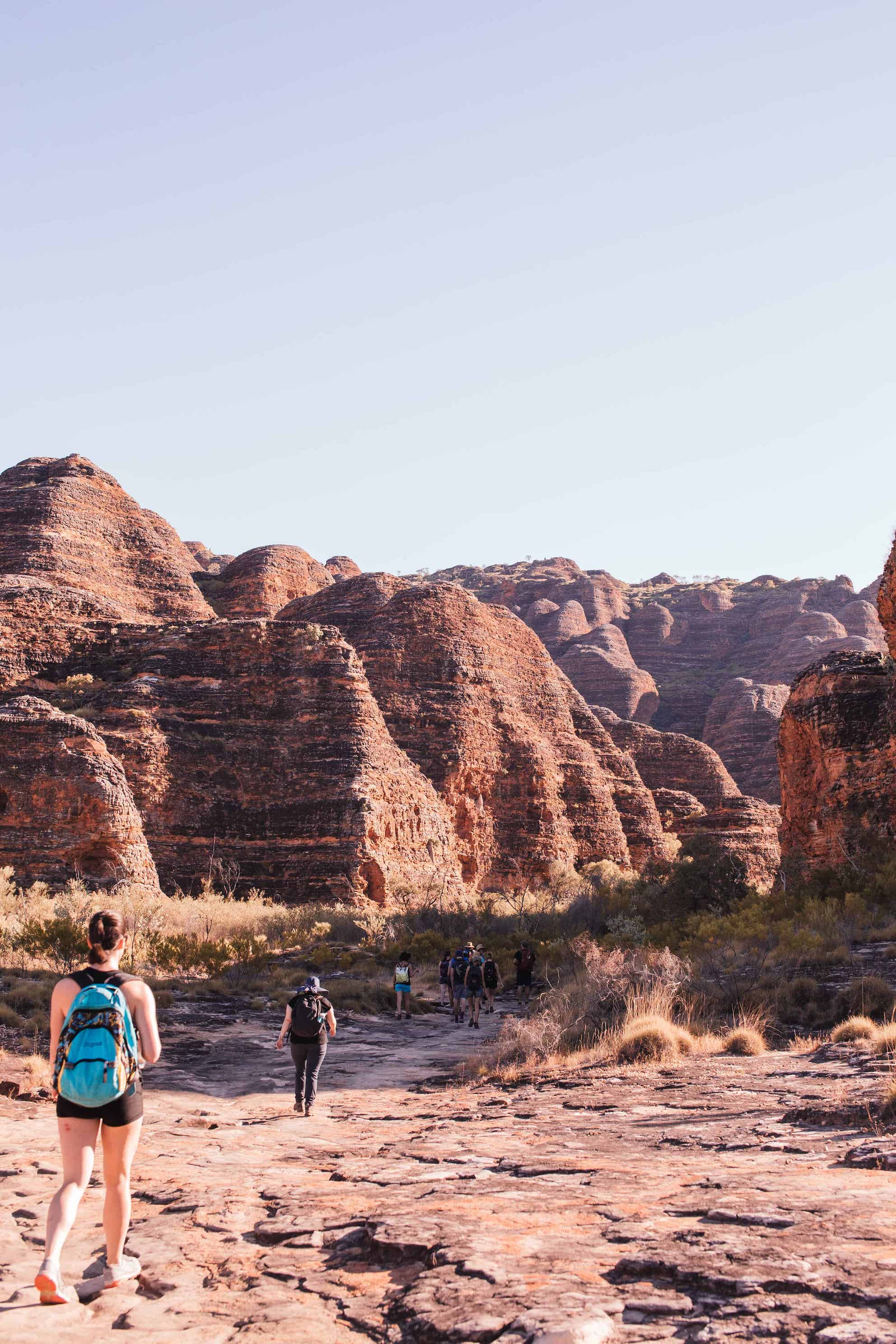 A group of friends using the AllTrails app to go for a hike. they are hiking through the red Australian outback.