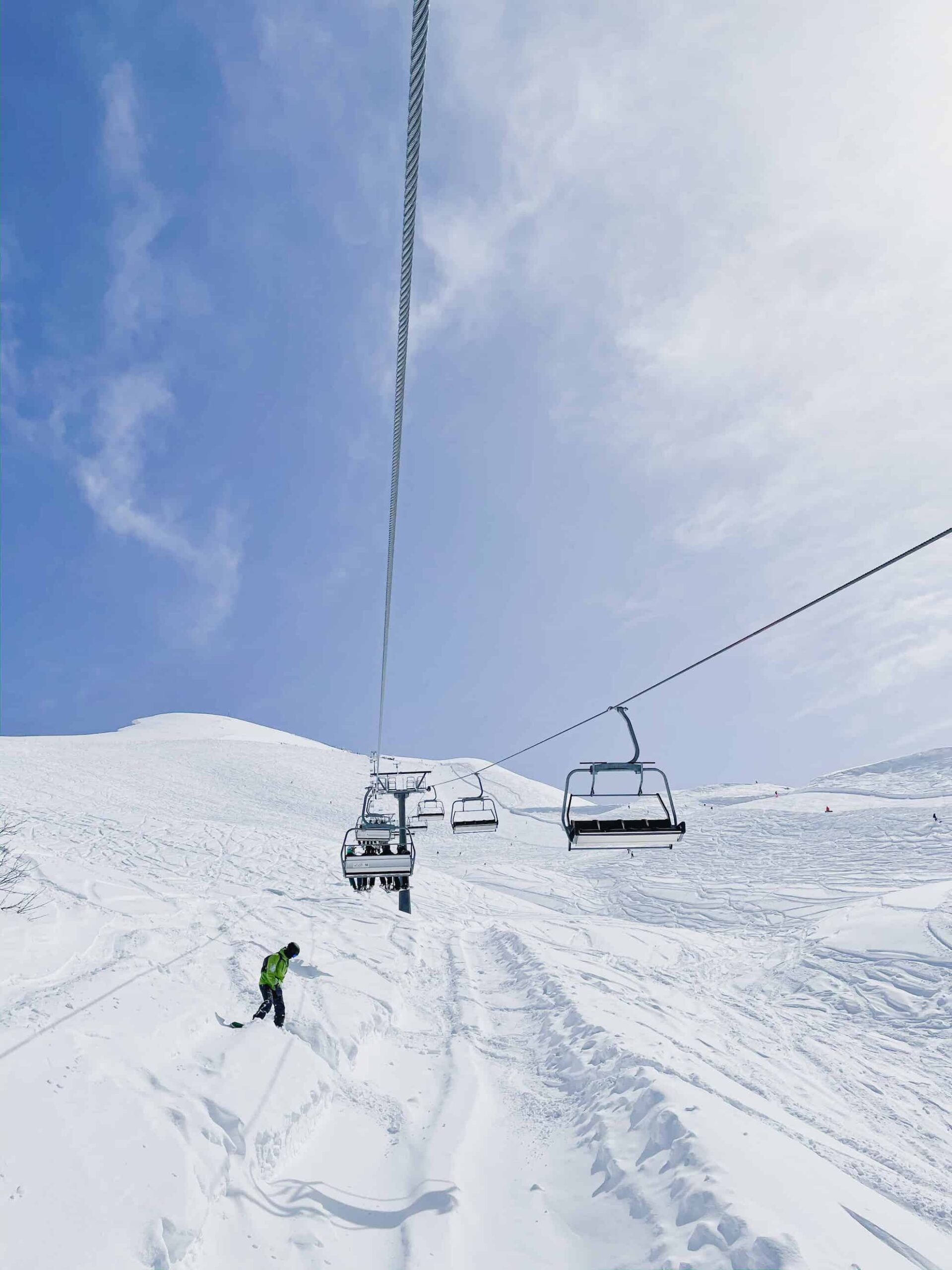 Chair lift running above one of my favourite ski runs that I found working a ski season at mount hotham. The sky is pale blue behind the chairlift