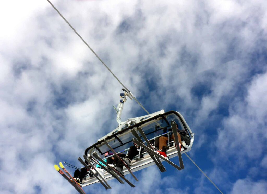 A hotham chairlift runs against a blue sky dotted with fluffy white clouds.